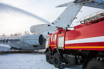 Fototapeta na wymiar Airfield fire truck extinguishes aircraft after emergency landing in a cold winter weather