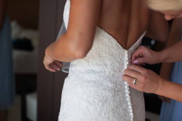 Obraz na płótnie Canvas Mom helps dress bride wedding dress from a back