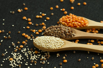 Three wood spoon with, quinoa lentil and buckwheat on black back