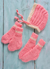 knitted clothes for newborn baby girl on wooden surface