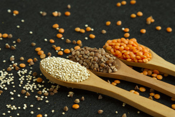Fototapeta na wymiar Three wood spoon with, quinoa lentil and buckwheat on black back