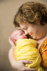 Mother kissing newborn baby. Yellow colored clothes