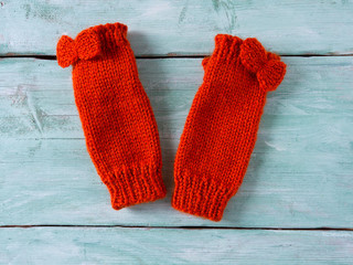orange hand knitted mittens on wooden surface