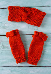 orange hand knitted headband and mittens on wooden surface