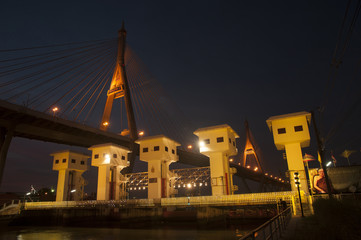 Floodgate with Bhumibol bridge in Thailand at night.