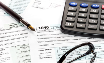 Pen, glasses and calculator on tax form 1040. business concept.