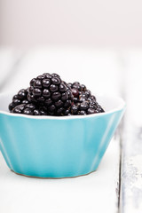 Björnbär i turkos skål på vit trä bakgrund