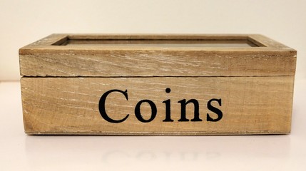 Wooden money chest filled with coins.