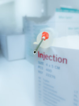 Injection needle on a box with medical supply. Extreme shallow depth of field with blurred background. 