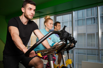 Obraz premium Young sportsmens on stationary bike