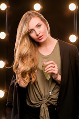 young blonde attractive woman in t-shirt and suit with glass of white sparkling wine on the stage