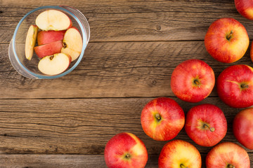 Sliced apples in a glass bowl on the old wooden table.