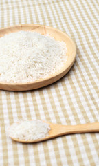 Uncooked white rice on wooden plate and spoon 