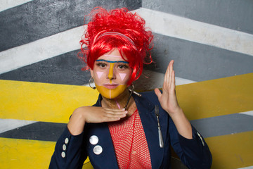 Retrato de chica joven con estética punk y post-punk (tribu urbana futurista) con peluca roja y con la cara pintada haciendo gestos provocativos