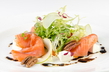 Marinated salmon with feta cheese, green apple, pecan and soy sauce on a plate on a white background, closeup