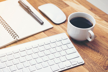 Coffee cup and keyboard computer notebook on wooden table background