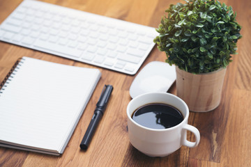 Coffee cup and keyboard computer notebook on wooden table background