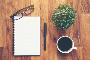 Coffee cup and notebook lens pen on wooden table background