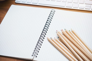 Keyboard computer and notebook on wooden table background