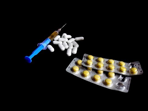 Injection syringe and medical drug pills on black background