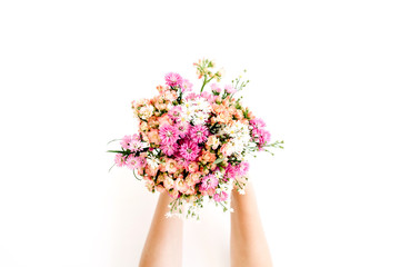 Girl's hands holding wildflowers bouquet on white background. Flat lay, top view