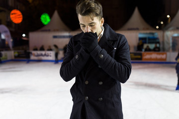 Handsome young man ice skating on rink outdoors.