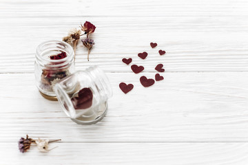 stylish hearts in glass jar and roses on white wooden background