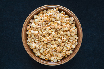 Dried peas broken up in the bowl on the dark background. Healthy eating and lifestyle.