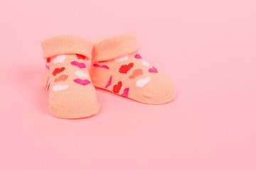 Obraz na płótnie Canvas Baby socks with hearts on a pink background