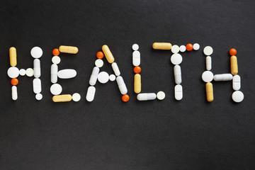 Word HEALTH made of various pills on black background