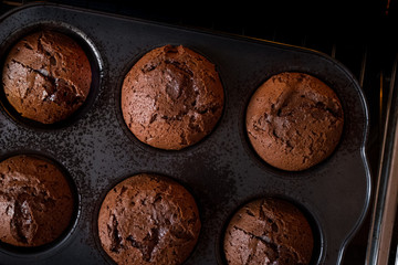 Fondant cake in home oven on the dark black background with chef hand. Good for menu recipe book design. Flat top view, horizontal, overhead.