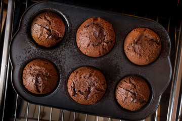 Chocolate fondant cake in home oven on the dark black background with chef hand. Good for menu receipt book design. Flat top view, horizontal, overhead.
