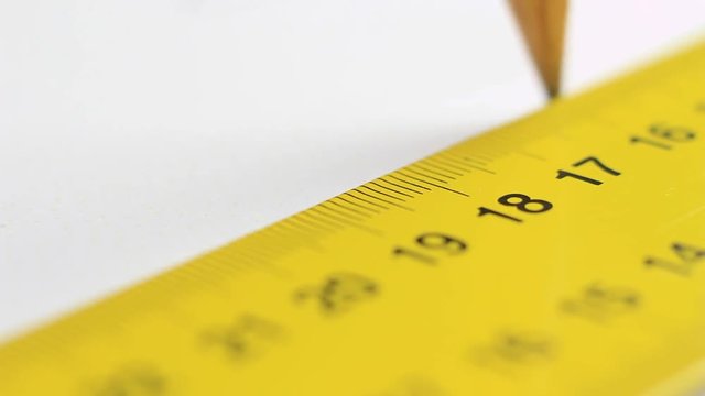 Using a ruler and a pen to draw on white paper.