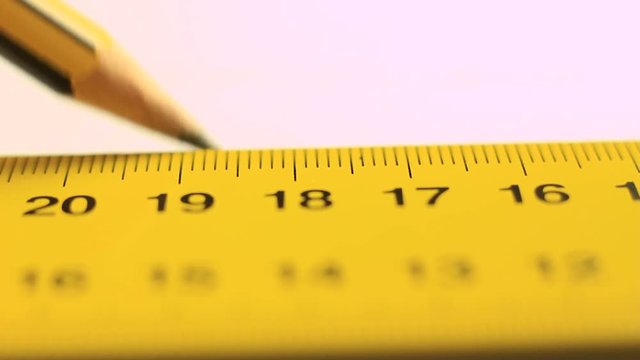 Using a ruler and a pen to draw on white paper.