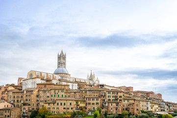 Fototapeta na wymiar Panoramic view of the historic city of Siena with the cathedral on a cloudy day in Tuscany, Italy.