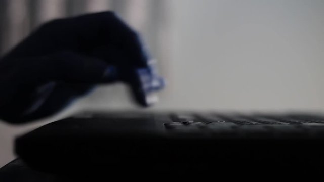Shadow, silhouette of a male palm hand, typing on the laptop keyboard in the darkness.