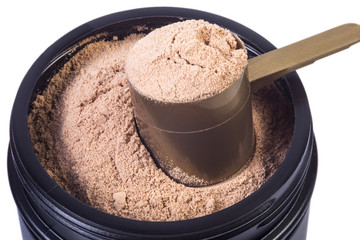 Macro image of protein for fitness and bodybuilding. Black jar with whey caramel protein. Scoop full of protein in the jar. Isolated on White background, macro image.