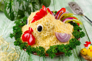 Salad shaped rooster on a plate on a wooden table
