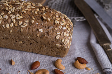 Whole grain bread put on kitchen napkin decorated with almond with a chef holding dough roller at the background.