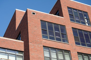 Modern industrial style residential building exterior with red bricks and glass windows