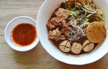 rice vermicelli topping pork ball and meat in brown soup with spicy sauce