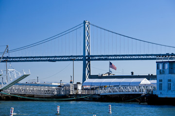 american flag in pier seven, blue sky and oakland bridge san francisco, california, united states