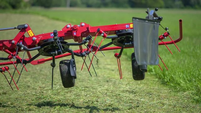 A young farmer is rushing to open rotary hay rakes manually as something got stick and he needs to fix the problem.
