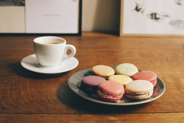 Fresh morning espresso coffee and some french macarons dessert on the wooden table background