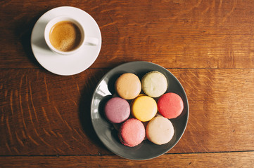 Fresh morning espresso coffee and some french macarons dessert on the wooden table background
