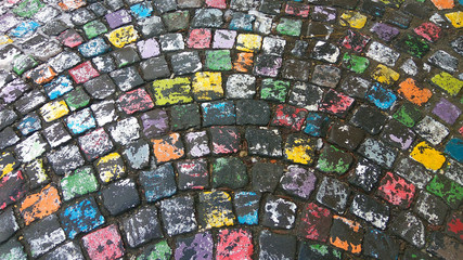 Many colored painted cobble stone pavement in after rain