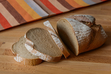 Brown bread loaf with slices on the table with cloth