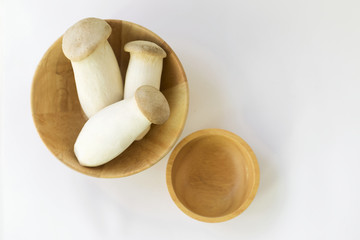 Fresh Eryngii mushroom in wooden bowl on white background