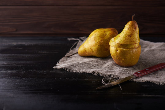 cutted pears and knife on wooden rustic background.