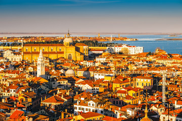 Naklejka premium Aerial view of Venice, Italy, at sunset with rooftops of buildings and warm sunlight.